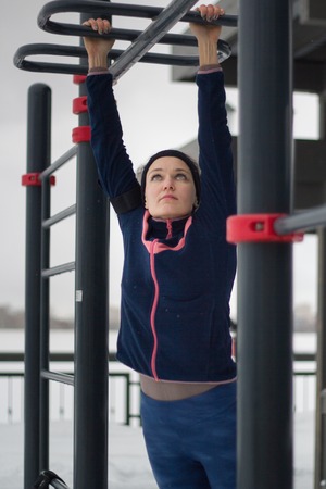 Young sport woman doing power exercises on work out fitness at snow winter parkの写真素材