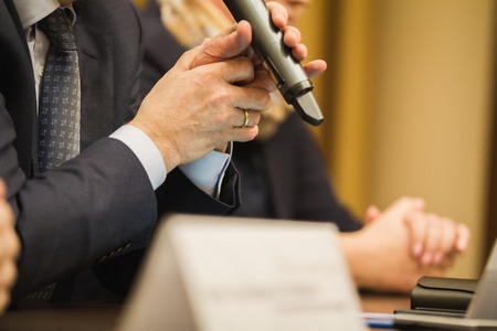 Businessmans holds microphone at conference or meeting, financial conceptの写真素材