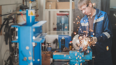 Professional car service - worker grinding metal construction with a circular saw, close upの写真素材