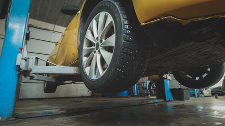 Car service - lifted yellow automobile in garage workshopの写真素材