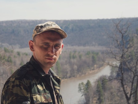 Adult man in military uniform at mount rock river - traveling concept, close upの写真素材