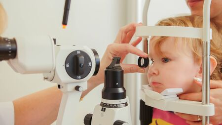 Doctor optometrist checks eyesight at little girl - childs ophthalmologyの写真素材