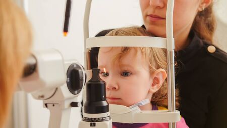 Childs healthcare - little girl with mother in ophthalmological clinic checks eyesightの写真素材