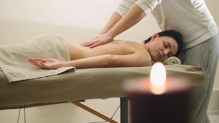 Oil massage - mans hands on the back of the half-nude pretty girlの写真素材