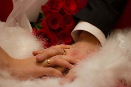 Hands of man and woman with wedding ring - fur and rosesの写真素材