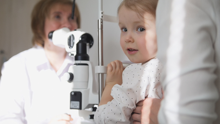 Little adorable girl in childs ophthalmology - optometrist checking eyesightの写真素材