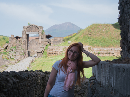 Beautiful red hair woman in glasses and shorts standing in pompeii, Italy - hot summer midday, horizontalの写真素材