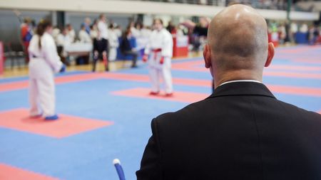 Martial art competitions - bald man coach-judge looking at karate teenagers fightingの写真素材