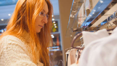Portrait a woman in glasses at clothing store chose a dress - shopping conceptの写真素材