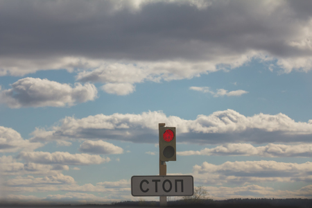 Sign STOP and traffic lights with red against clouds and skyの写真素材