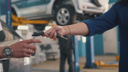 Car workshop - woman gives the keys of car for mechanicの写真素材
