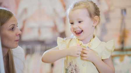 Happy little girl tries on summer shirt in storeの写真素材
