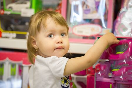 Happy little girl chooses toys in a childrens storeの写真素材