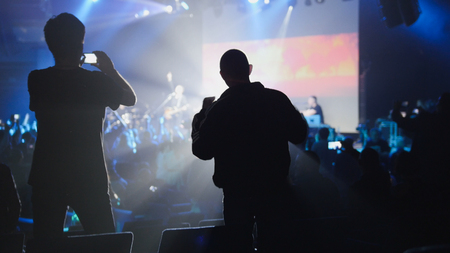 Shadows of people making a video of the concert on a mobile phoneの写真素材