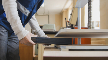 Printing process in printing press machine - worker inserts paper sheets, close upの写真素材