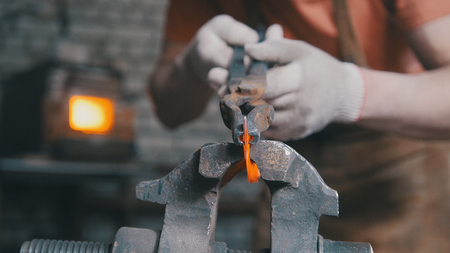 Blacksmith with gloves in forge makes steel knife