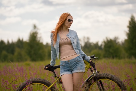 Girl on a bicycle at a flower meadowの写真素材