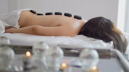 Stones on the back of a girl in a stone therapy roomの写真素材