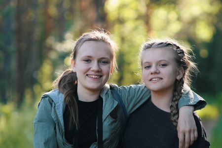 Two pretty girls sisters teenagers friends in park - summer outdoor