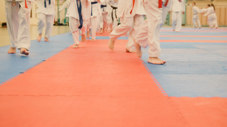 Karate training - young sportsmen in kimono runs on tatami in the gymの写真素材
