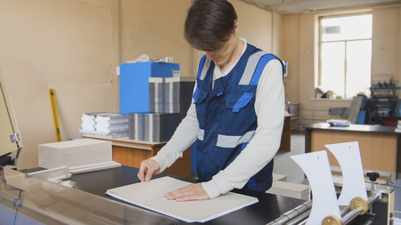 The operator of the printing house works at the typographical machine