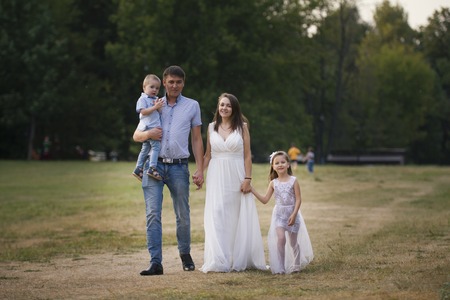 Healthy family walking in the park at summer evening - father, mammy, daughter and little boyの写真素材