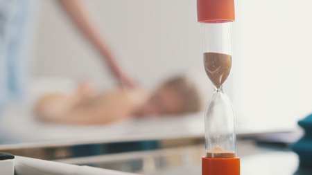 Sand clock in cabinet of tibetan medicine - massage for young blonde woman