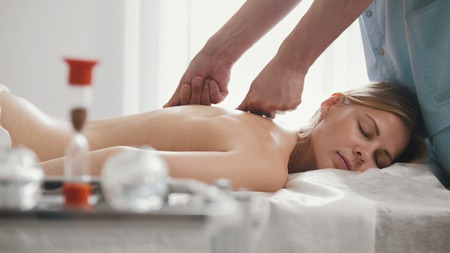 Male physiotherapist massaging womans back in the medical officeの写真素材