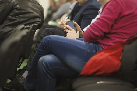 Man employee in suit uses digital device sitting on the forum about industry and economyの写真素材