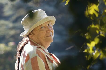 Senior happy woman smiling in the paek or garden