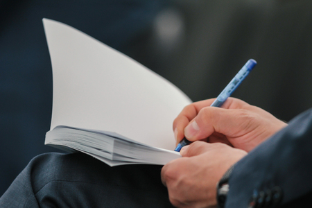 Business people hand in suit writing on notebook at lecture or seminar, close upの写真素材