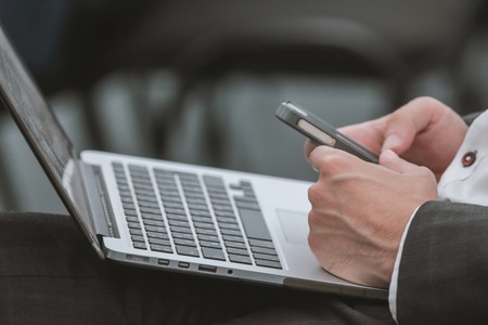 Businessman working with laptop and smartphone at seminar - close upの写真素材