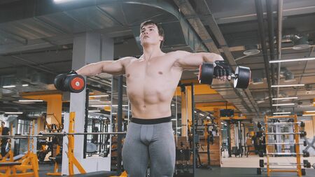 Athlete man lifting dumbbells without shirt in the gymの写真素材