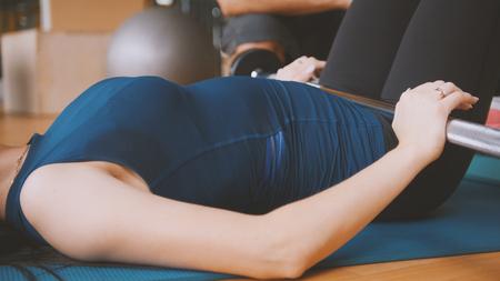 Young attractive brunette women doing exercise for buttocks - the rise of a body lying over the barの写真素材
