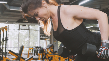 Woman athlete lifting dumbbells in the gym - close upの写真素材