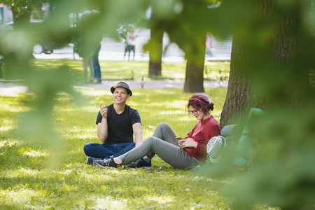 Young couple tourists with backpacks have rest in the parkの写真素材