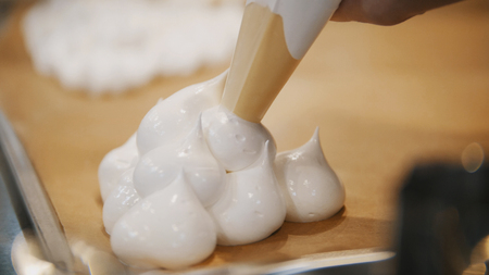 Cooking Pavlova Dessert meringue - pastry tube spread meringue on a baking sheetの写真素材