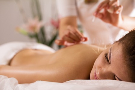 The doctor sticks needles into the womans body on the acupunctureの写真素材