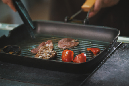 chef is frying meat and vegetables in a panの写真素材