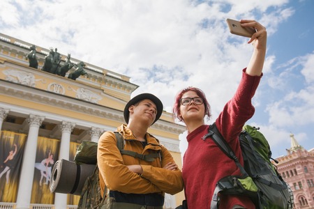 Young couple of tourists taking selfies against the Bolshoi theatre in Saint-Petersburgの写真素材