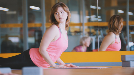 Athletic female shows yoga exercises for women in fitness club