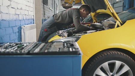 Mechanic in car service - repairing in engine compartmentの写真素材