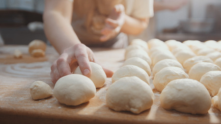 Cooks roll the dough for baking, pieces of raw dough on the wooden Boardの写真素材