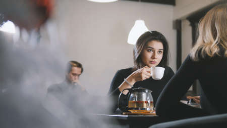 Pretty young woman drinking coffee and smiling in the cafeの写真素材