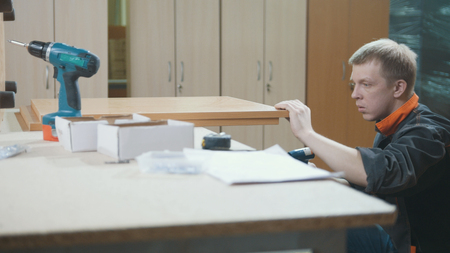 Worker carpenter is screwing chair leg at a furniture factoryの写真素材