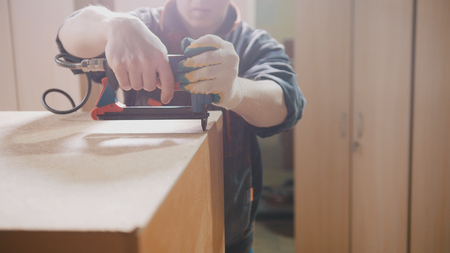 Carpenter working with an electric industrial stapler on the factory, fixing furniture details, industryの写真素材