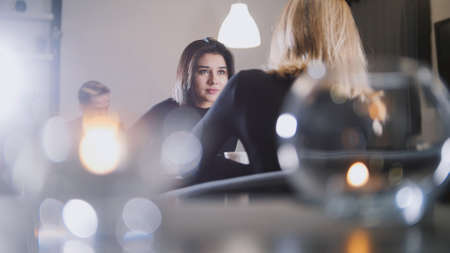Pretty young woman with black hair drinking coffee and talking with girlfriend in the cafeの写真素材