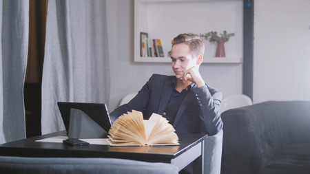 Young man sitting with notebook and book in cafe with coffeeの写真素材