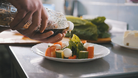 Chef serves salad on the plate in restaurantの写真素材