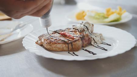 Chef serves meat on the plate - red pepper and sauce, close-upの写真素材